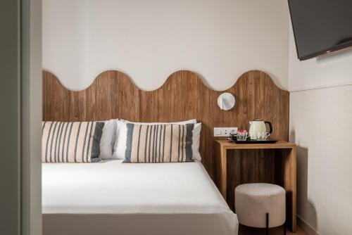 a bedroom with a bed with a wooden headboard and a stool at BYPILLOW Paseo in Alicante