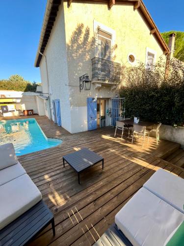 une terrasse en bois à côté d'une maison avec une piscine dans l'établissement Villa Jardin piscine proche Centre-ville 10 mn des plages, à Montpellier