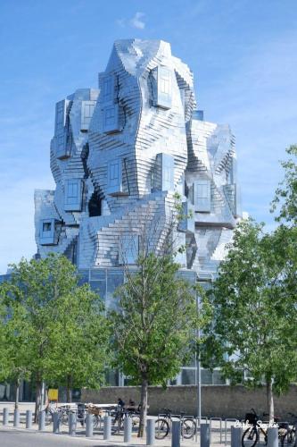 a tall building with a facade with trees in front of it at Les Mélias in Arpaillargues-et-Aureillac