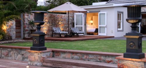a patio with a table and chairs and an umbrella at The Gregoire Boutique Villa in Hermanus
