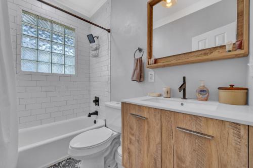 a bathroom with a toilet and a sink and a mirror at 1920s Bungalow with King bed WIFI Fenced backyard in Atlanta