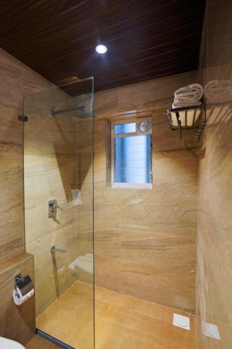 a bathroom with a shower with a glass door at Hotel Everest Regency Pune in Pune
