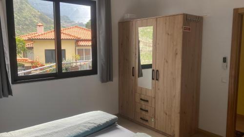 a bedroom with a wooden cabinet and a window at Casa Azul in São Vicente