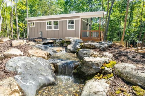 a small house with a pond and rocks in front of it at Elevate Tree House Community in Pittsboro