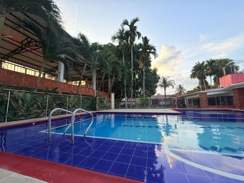 a large blue swimming pool with palm trees in the background at Quinta de san pedro in Villavicencio