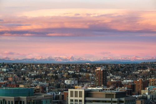 a city skyline with mountains in the background at Poolside Bliss w Rocky MTN & Tower Views - FREE Banff Pass, Outdoor Pool, Parking, Gym, & Wine! in Calgary