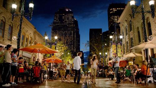a group of people walking down a city street at night at Poolside Bliss w Rocky MTN & Tower Views - FREE Banff Pass, Outdoor Pool, Parking, Gym, & Wine! in Calgary