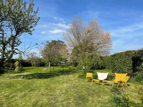 un groupe de chaises jaunes assises dans un champ dans l'établissement Maison Hestia - Collection Idylliq, à Épégard