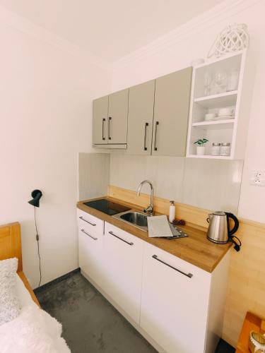 a kitchen with white cabinets and a sink at Štúdio Srnček - Tatranská Štrba - wellness, bazén in Štrba