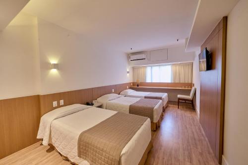 a hotel room with three beds and a window at South American Copacabana Hotel in Rio de Janeiro