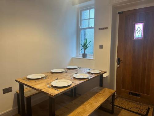 a wooden table with plates on it in a room at Charming newly renovated 3 bed cottage in Brecon town with private garden & pets welcome in Brecon