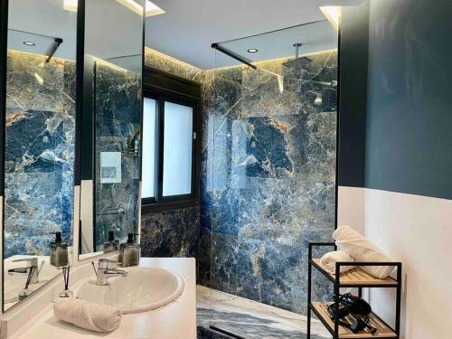 a bathroom with a sink and a glass shower at Sky Blue Suite - Terrace & Ocean View 2BR in Tangier