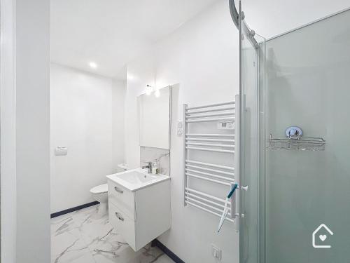 une salle de bain blanche avec une douche et un lavabo dans l'établissement Résidence Beaux Rêves, à Châtellerault