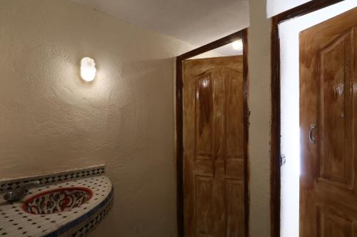 a bathroom with a toilet and a door with a mirror at Gite Ogog Tacheddirt in Tacheddirt
