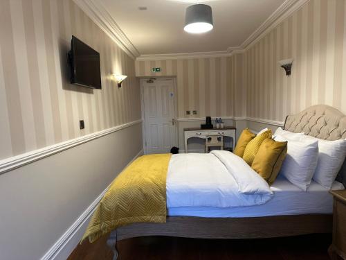 a bedroom with a bed with yellow and white pillows at Sweeney's Hotel 2020 Limited in Dungloe