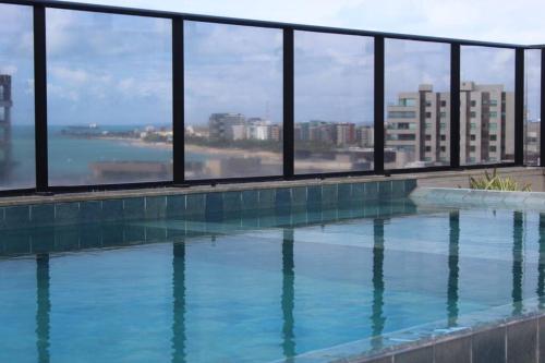 a swimming pool with a view of the water at Edf Time, completo e aconchegante, bem localizado in Maceió
