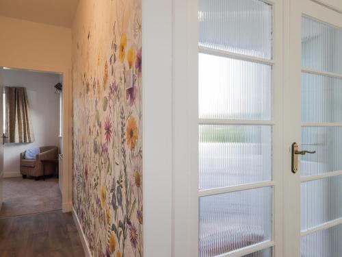 a hallway with a sliding door with a floral wallpaper at Avemar in Buckie