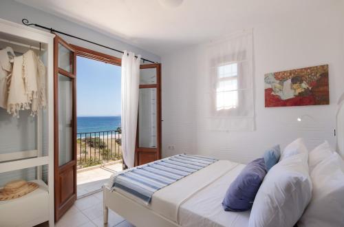 a bedroom with a bed and a balcony with the ocean at Apiliotis sunrise beach villa in Ligaridia