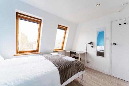 a white bedroom with a bed and a desk at White City Double Rooms in London