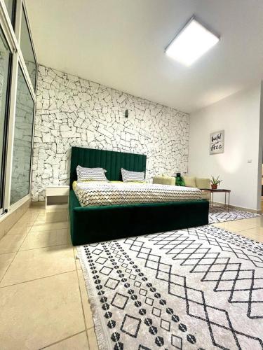 ein Schlafzimmer mit einem grünen Bett und einer Steinmauer in der Unterkunft Studio Meublé de Haut Standing in Abidjan
