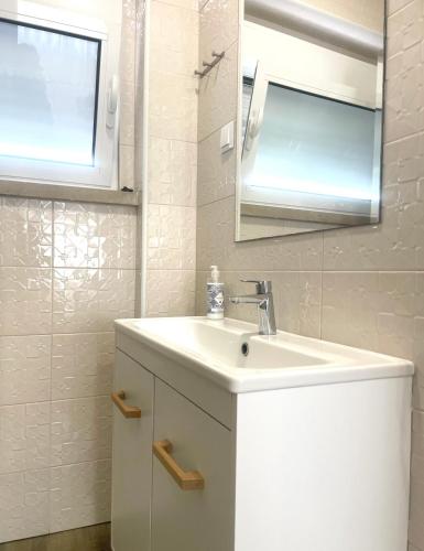 a white bathroom with a sink and a mirror at Vila Alexandra in Costa da Caparica