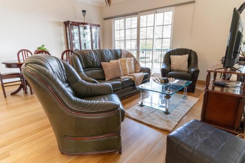 a living room with a leather couch and chairs at Varandas da Caldeira by Madeira ReAL in Câmara de Lobos