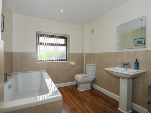 a bathroom with a tub and a toilet and a sink at Yr Hen Stabl in Caernarfon