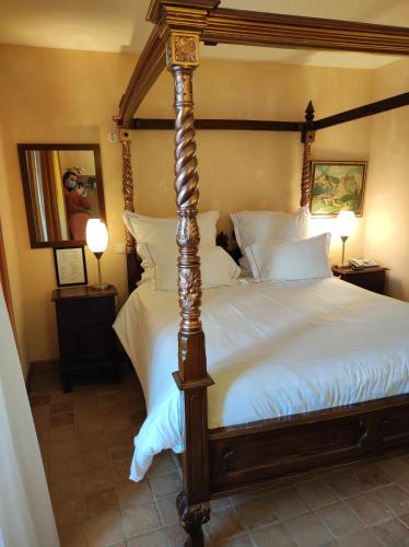 a bedroom with a canopy bed with white sheets at Hostellerie Les Hauts De Sainte Maure in Sainte-Maure-de-Touraine