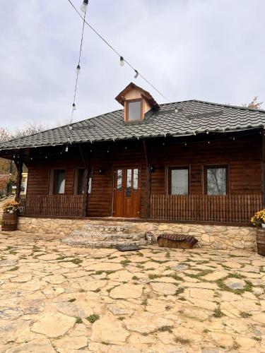 a log house with a stone patio in front of it at Crâșma Trei Fântâni - Cebotaru in Hogineşti