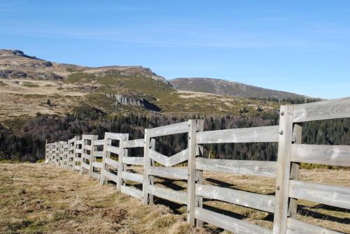 a white fence on a hill with mountains in the background at The Originals Access, Hôtel Saint-Flour in Saint-Flour