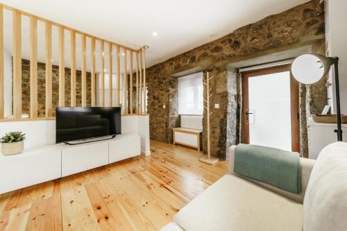 a living room with a television on a white couch at Casa do Castelo in Covilhã