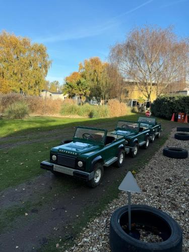 two green trucks parked next to a pile of tires at Hot tub retreat at Tattershall Lakes in Tattershall