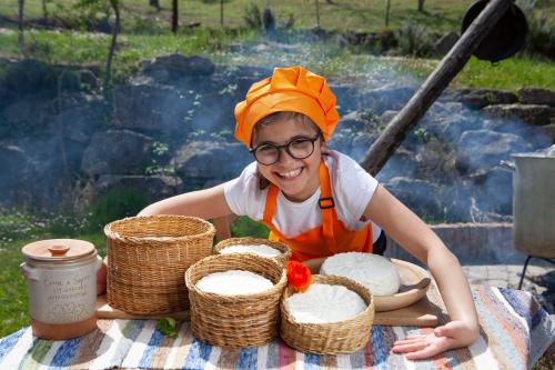 a young girl wearing an orange hat sitting at a table with baskets at Agriturismo Terra e Sapori in Campodipietra