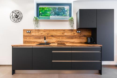 a kitchen with black cabinets and a wooden counter top at Lion PARKK Apartments in Kníničky
