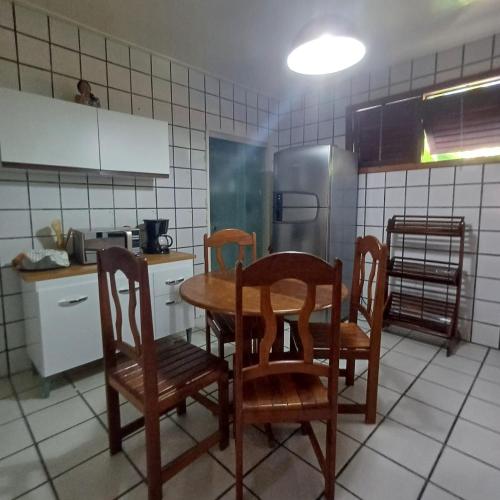 a kitchen with a table and chairs and a refrigerator at Casa Gaúcho in Morro de São Paulo