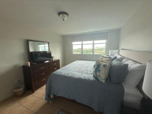 a bedroom with a bed and a dresser and a television at Ocean & Marina Views 3 Bedroom 2 Bathroom Luxury Condo in Fajardo