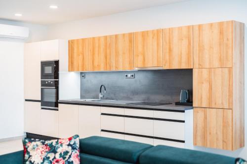 a kitchen with wooden cabinets and a blue couch at Lion PARKK Apartments in Kníničky