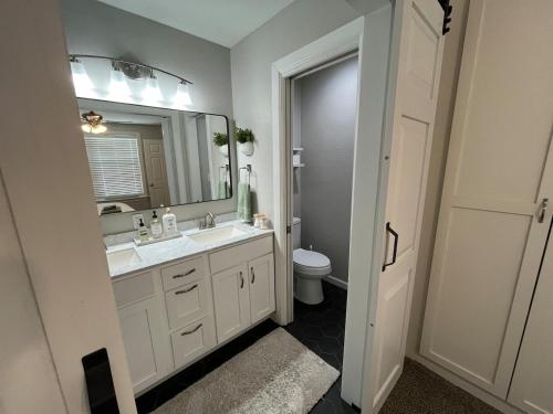 a bathroom with a sink and a mirror and a toilet at Rt 66 Fairgrounds Retreat By Tulsa Getaways in Tulsa