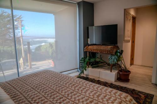 a bedroom with a bed and a large window at Hotel Boutique Aldea del Mar in Pichilemu