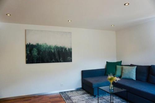 una sala de estar con un sofá azul y una pintura en Central Local Flat, en Zermatt