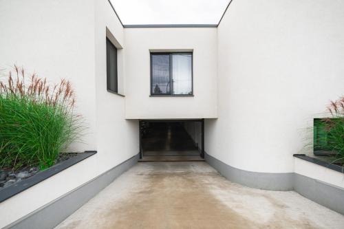 a hallway of a white building with a door and plants at Lion PARKK Apartments in Kníničky