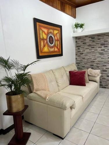 a couch in a living room with a painting on the wall at SJO airport 4 min free parking in Alajuela City