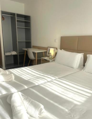 a bedroom with a large bed with white sheets at Vila Alexandra in Costa da Caparica