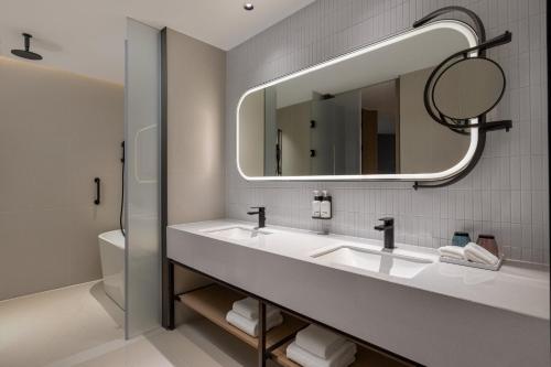 a bathroom with two sinks and a mirror at EVEN Hotel Shanghai Hongqiao CBD by IHG in Shanghai
