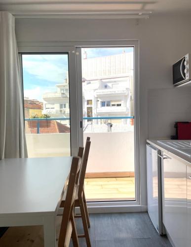 a kitchen with a table and a large window at Vila Alexandra in Costa da Caparica