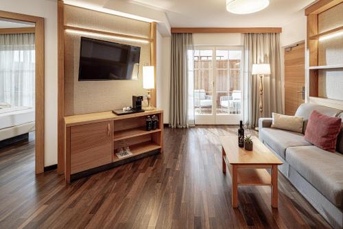 a living room with a couch and a tv at Lake Spa Hotel SEELEITEN in Caldaro