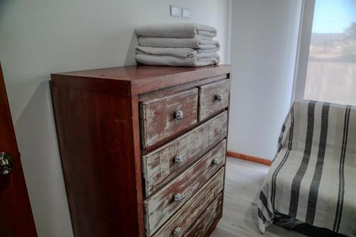a wooden dresser with a stack of towels on top at Hotel Boutique Aldea del Mar in Pichilemu