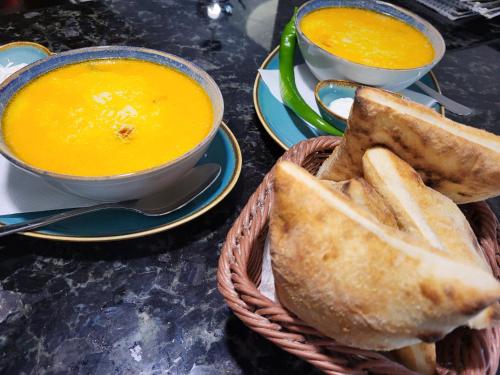 a basket with bread and a bowl of soup and two bowls of toast at Hanul Cappsha in Oradea