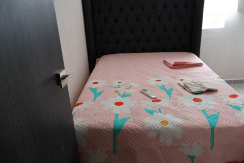 a bed with a pink bedspread with flowers on it at casa con club de playa in General Juan N Alvarez International Airport