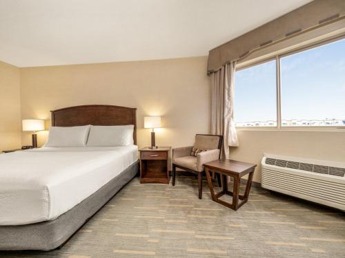 a hotel room with a bed and a chair and a window at Holiday Inn Lethbridge by IHG in Lethbridge